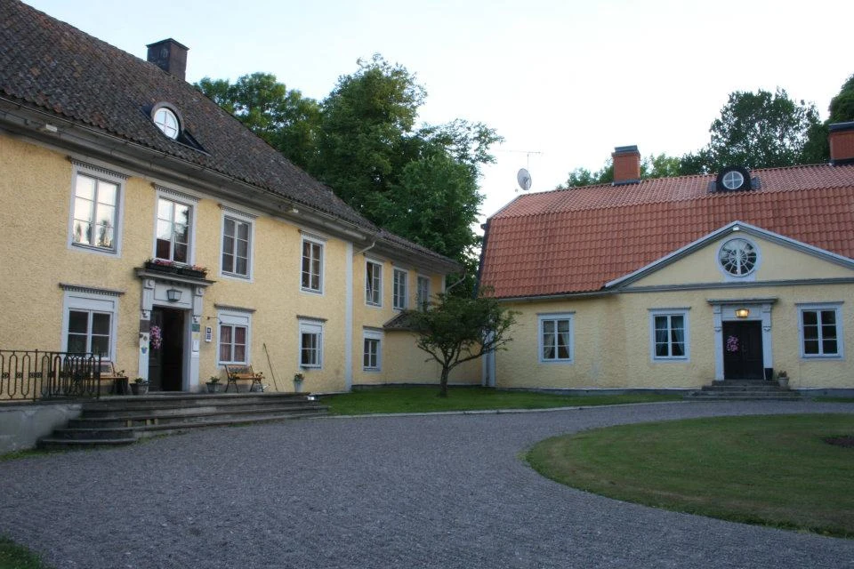 Aspa herrgårds gula huvudbyggnad sedd från parken