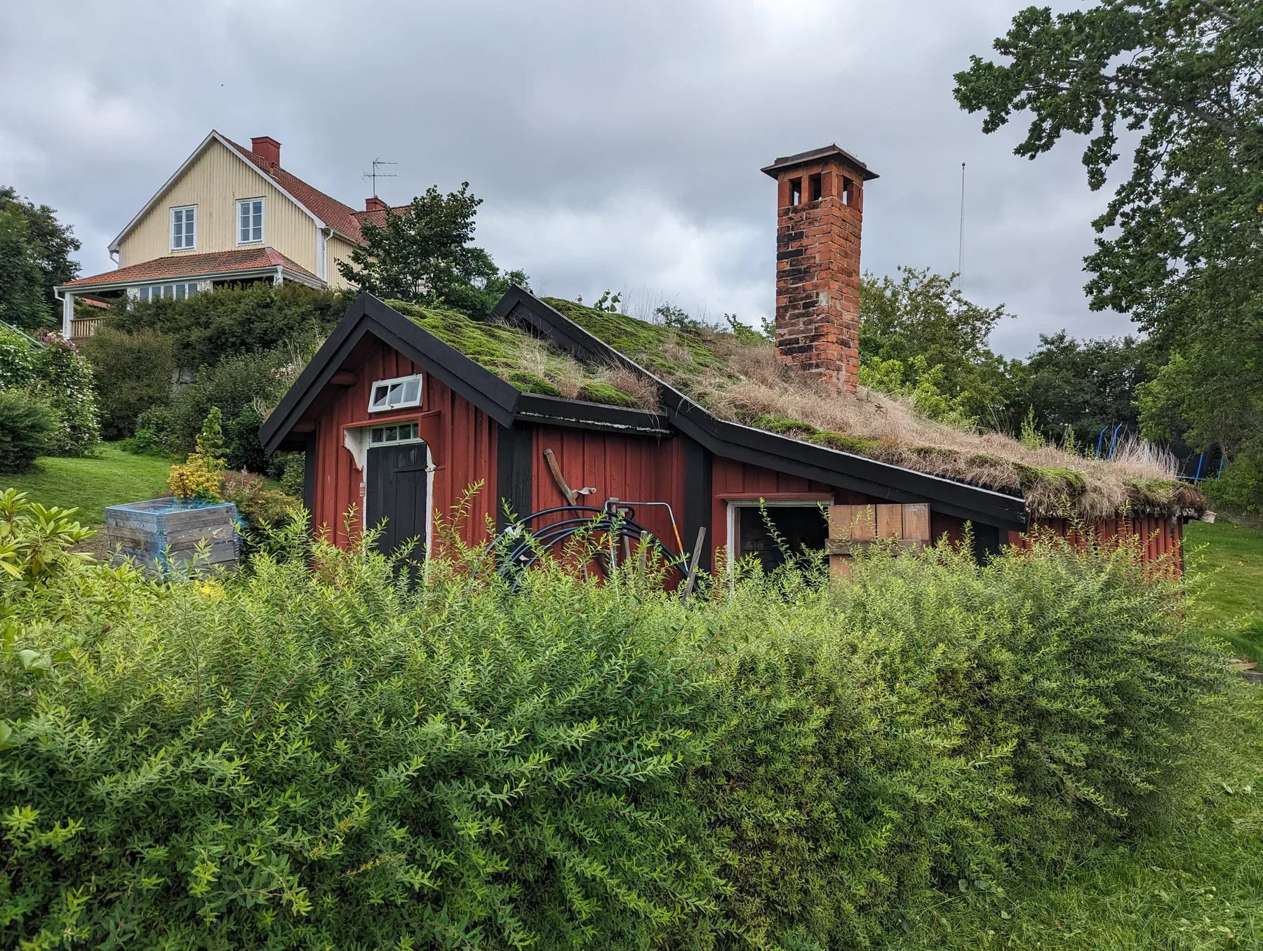 Sagers stuga i Askersund, ett rött trähus med torvtak och hög tegelskorsten