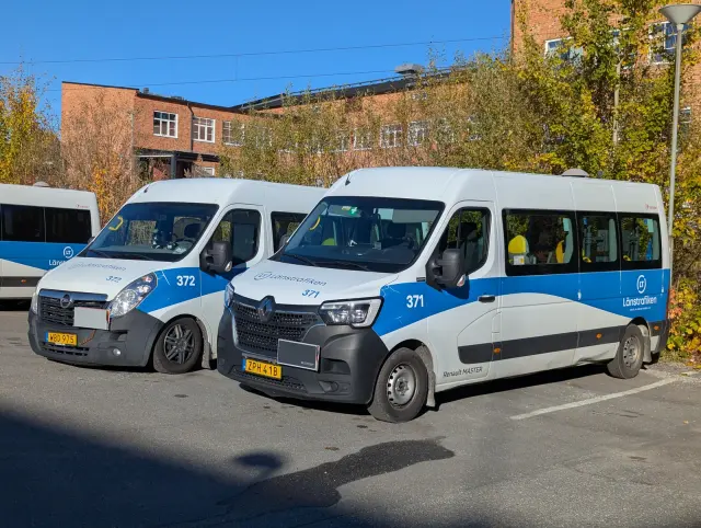 Två vita och blå Länstrafiken-fordon parkerade i Lindesberg – illustration av kollektivtrafik i Örebro län