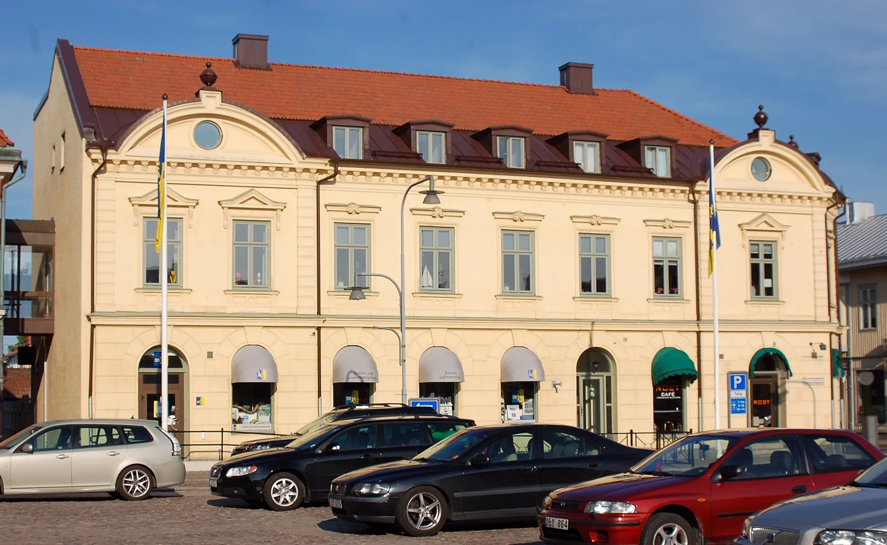 Ljus putsad byggnad och parkerade bilar vid Väderkvarnsgatan och torget i Askersund
